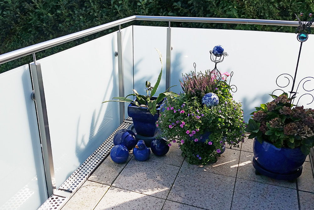 Die Edelstahlschlosserei Nappenfeld fertigte in Mülheim ein 6,5m langes Balkon-Geländer aus Edelstahl mit heruntergezogenen Glasscheiben, um die Dachrinne zu verkleiden