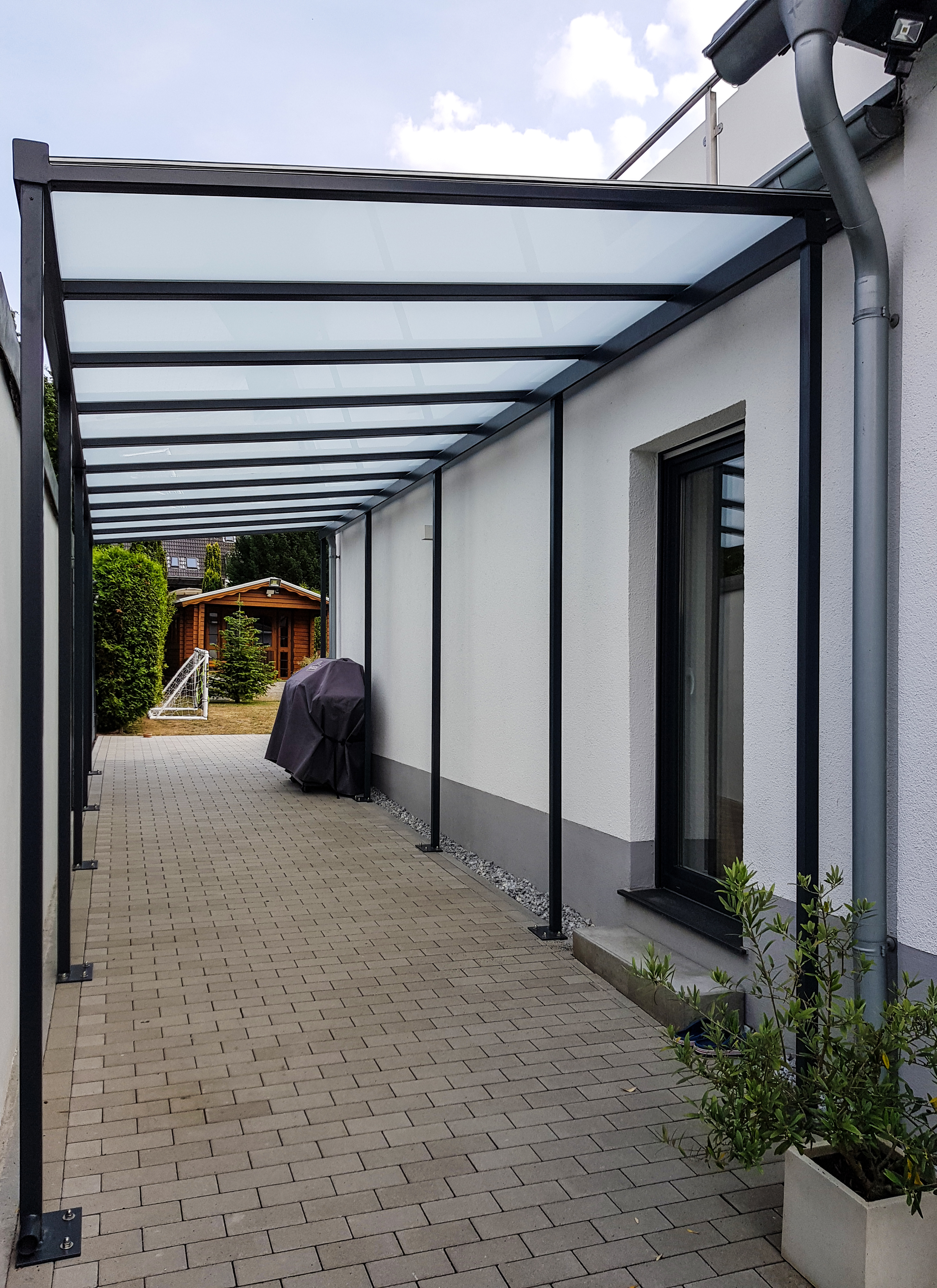 Edelstahlexperte Nappenfeld realisierte in Mülheim-Saarn eine Konstruktion, die Haus und Garage verbindet und die gepflasterte Fläche dazwischen großzügig überdach