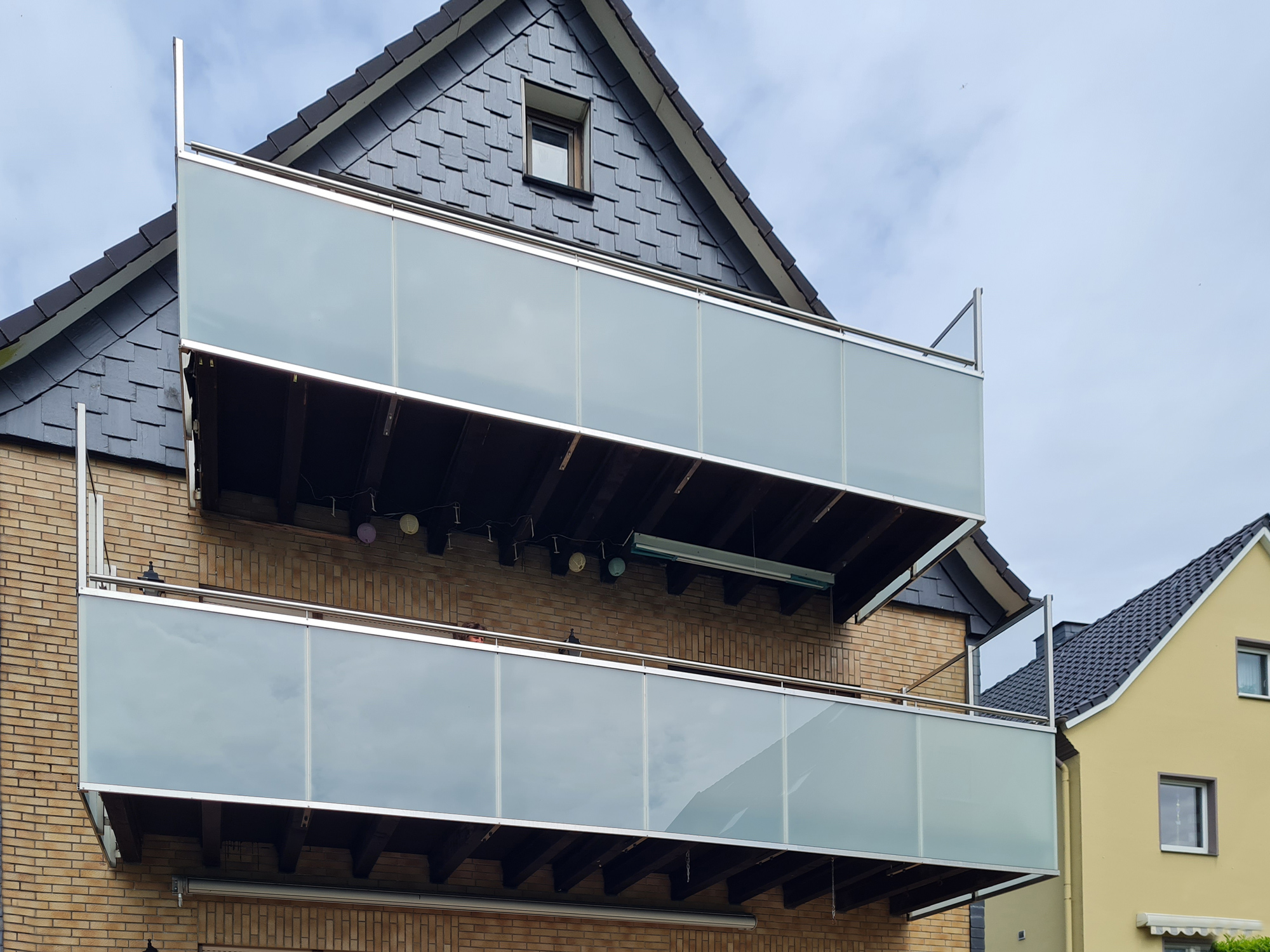 Zur Verkleidung zweier alter Holzbalkone fertigt die Bauschlosserei Nappenfeld ein Edelstahlgeländer mit integriertem Glas